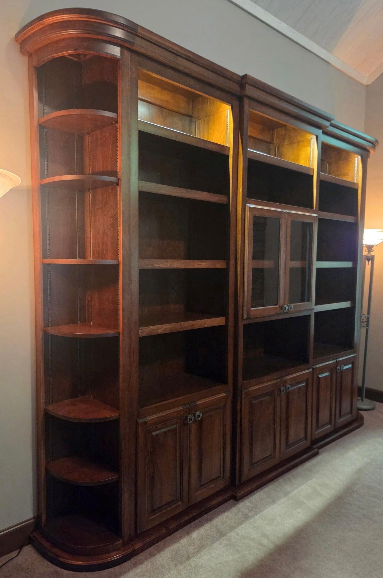 Dark wooden built-in bookshelf with glass cabinet tops and lower storage doors in a living room.
