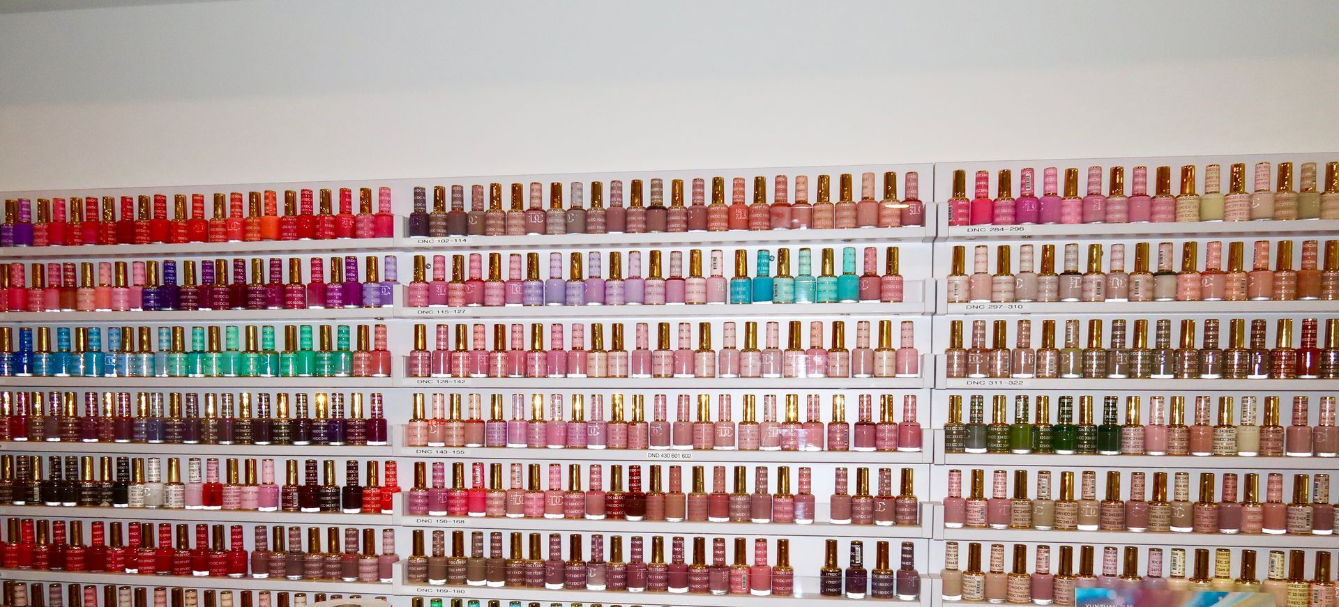 Shelves of colorful nail polish bottles arranged in rows inside a store.