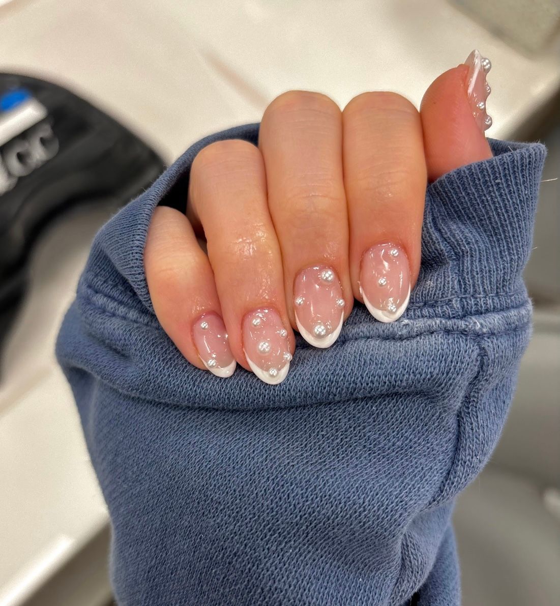 Hand with pink glitter French-tip nails holding a blue sleeve close-up