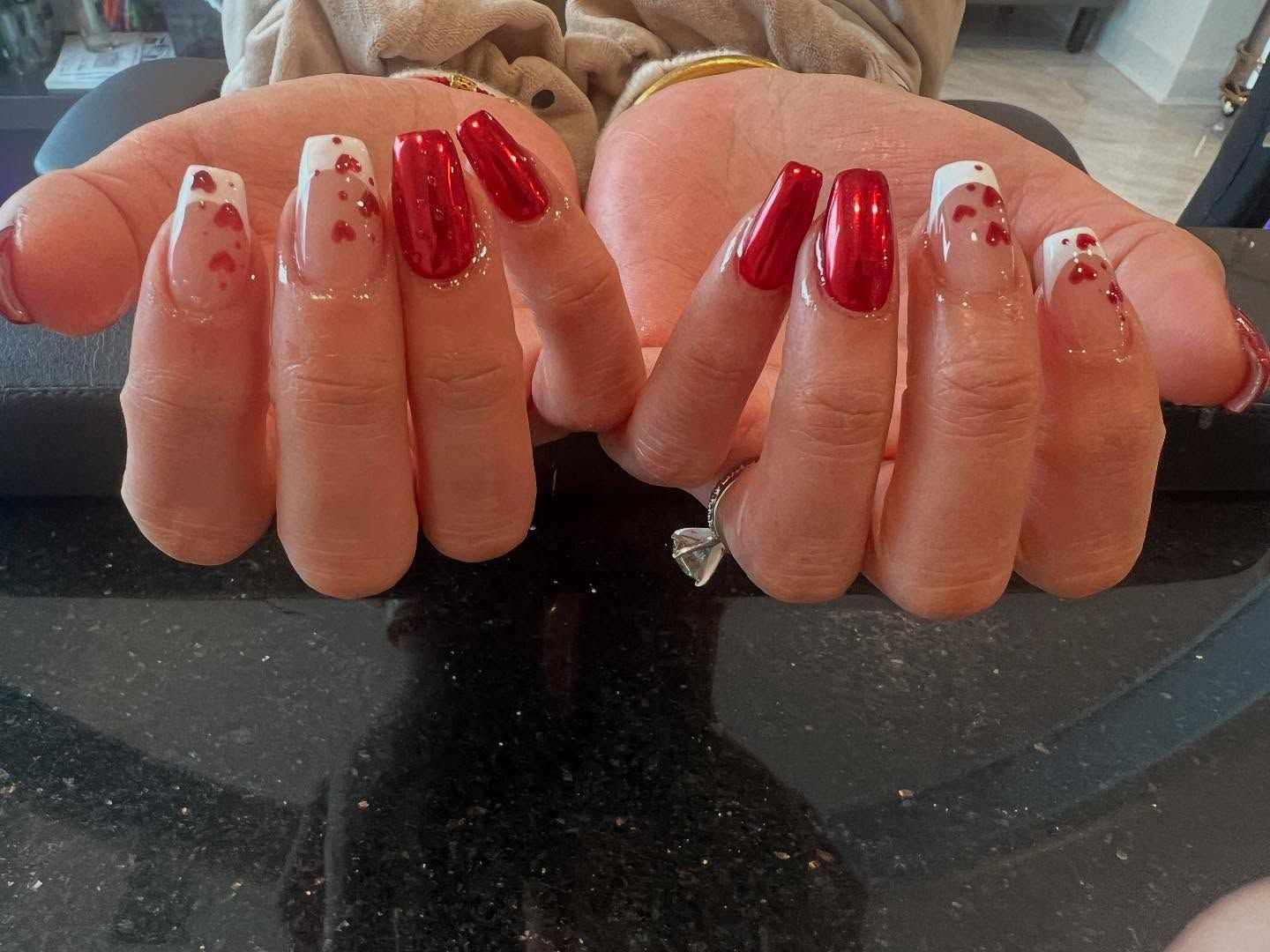 Hands with long, red and white tipped nails, some with heart designs.