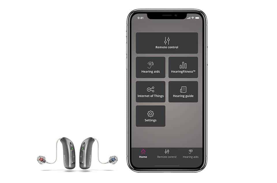 A pair of hearing aids sitting next to a cell phone.