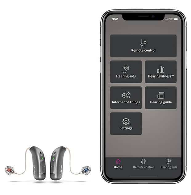 A pair of hearing aids next to a cell phone.