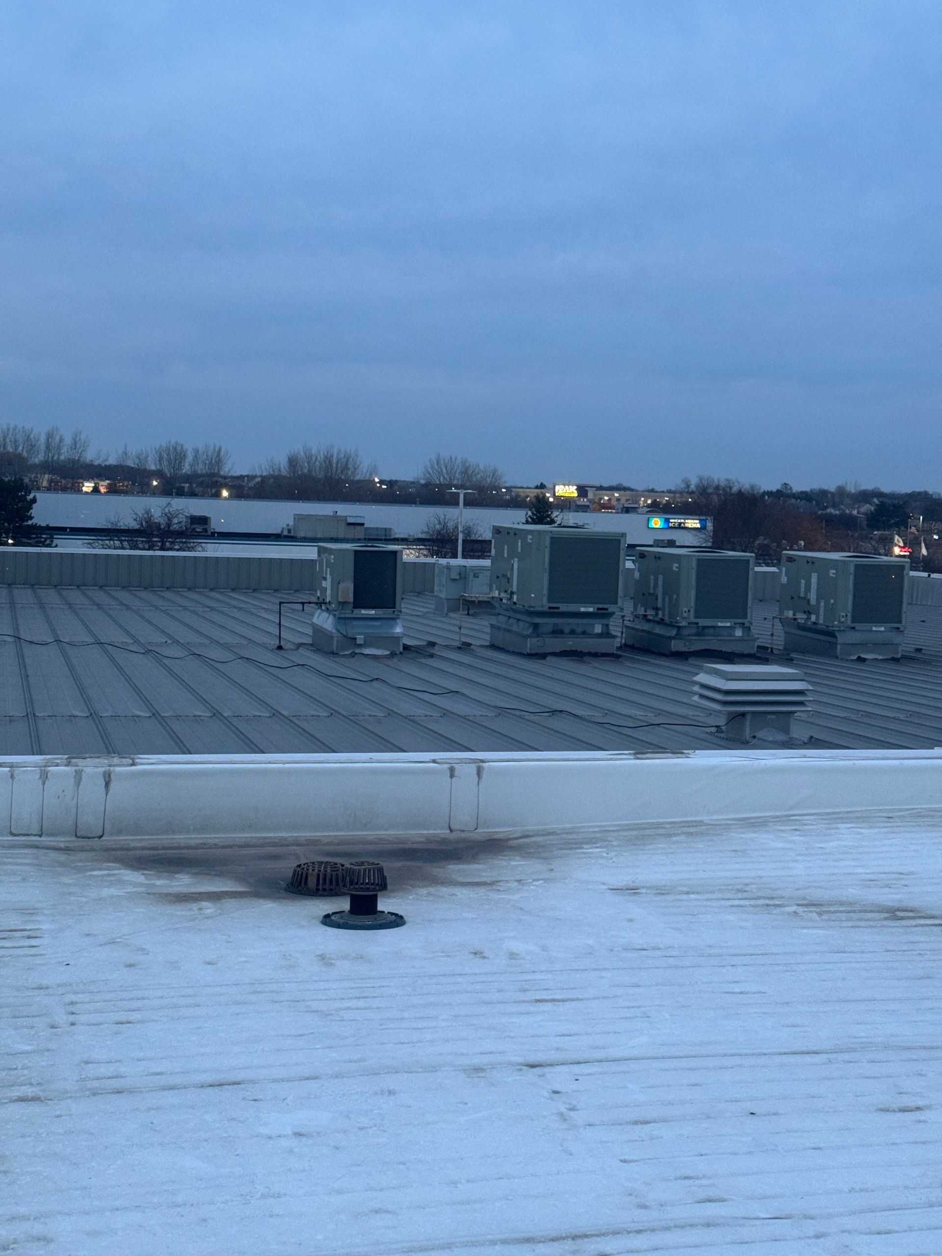 Rooftop view of commercial building with HVAC units, overcast sky.