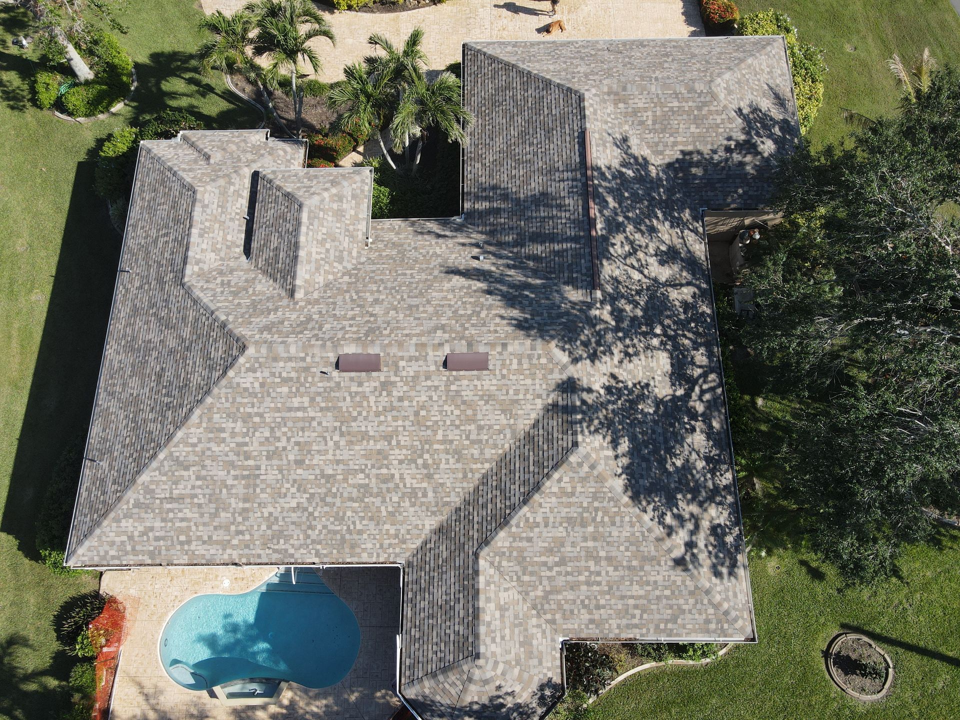 Overhead view of a house with a gray roof, a pool, and green grass.