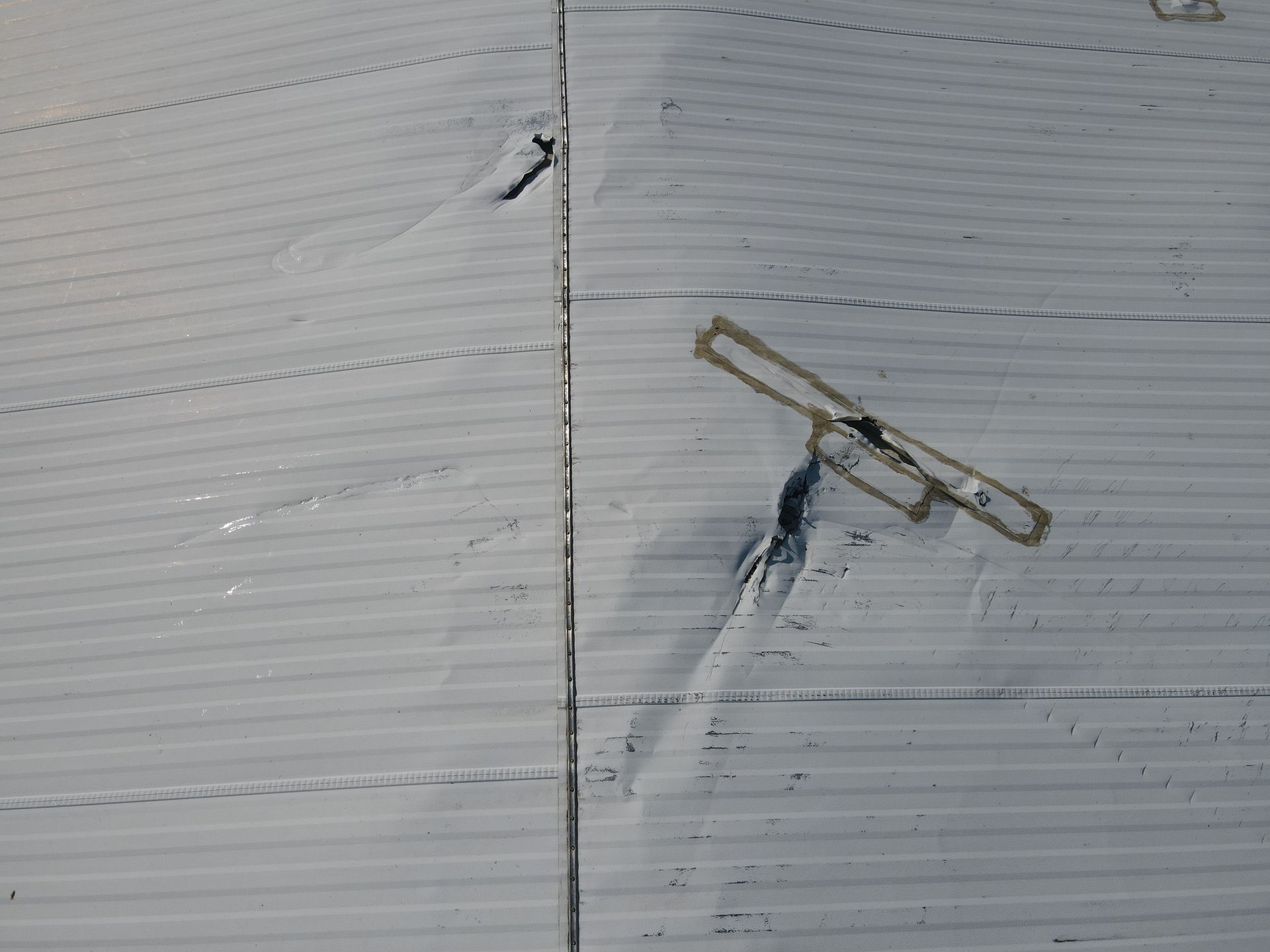 Gray corrugated metal surface with a dark, irregularly shaped object and a small, rectangular tag.