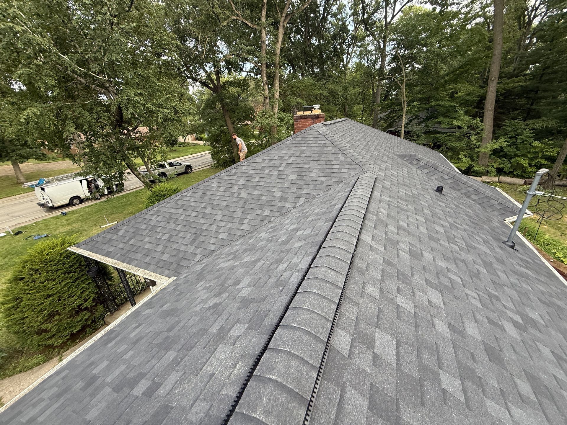 Newly shingled gray roof with trees in the background, likely a residential home.
