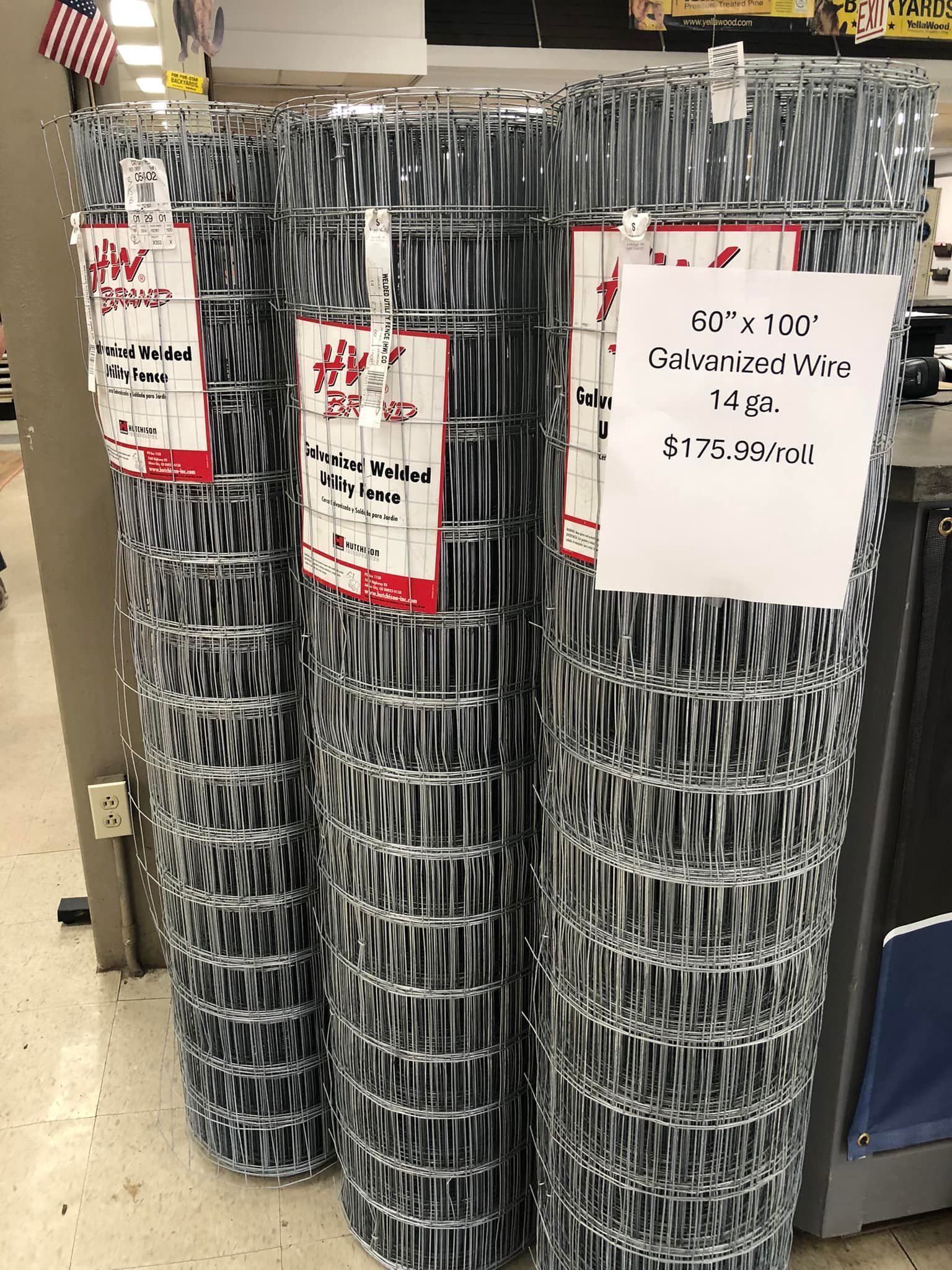 Three rolls of wire fence are stacked on top of each other in a store.