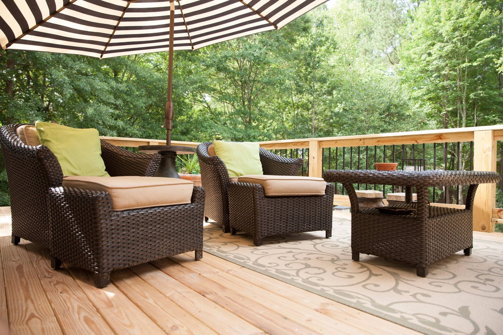 A deck with wicker furniture and a striped umbrella