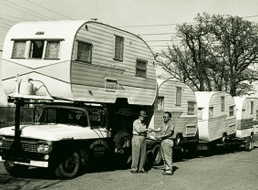 Two men standing next to a truck with a trailer on it