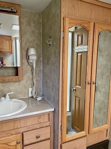 A bathroom in a rv with a sink , mirror , and closet.