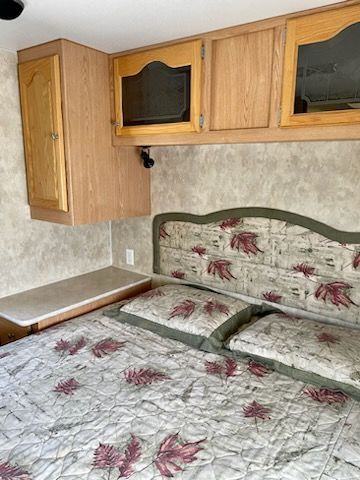A bedroom with a bed , cabinets , and a ceiling fan.