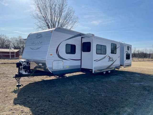 A white trailer is parked in a grassy field.