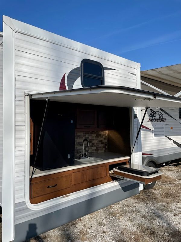 A white rv with the door open and a sink.