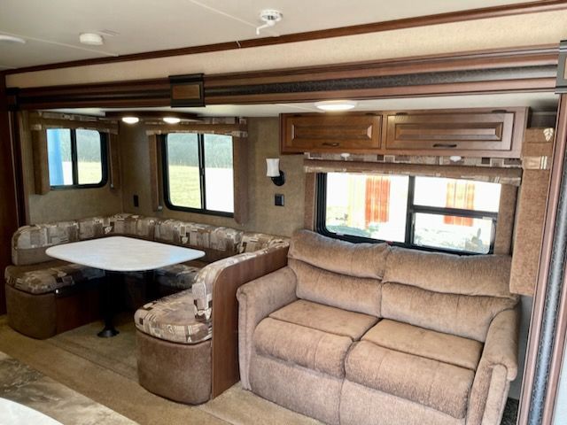 A kitchen in an RV with a sink, stove, microwave, and refrigerator.