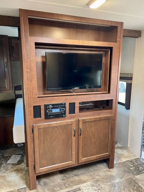A television is sitting on top of a wooden entertainment center.