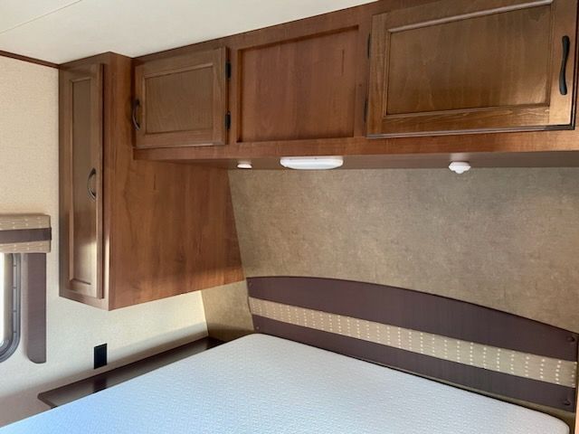 A bedroom with a bed, cabinets and a mirror.