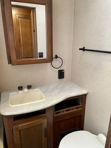A bathroom with a sink, toilet, and mirror.