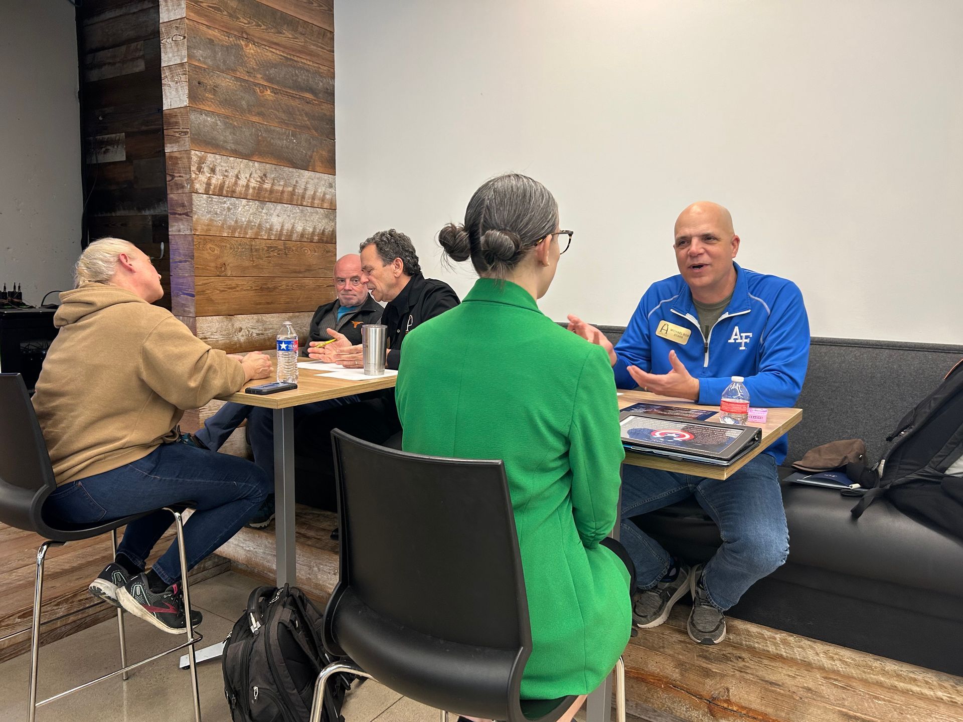 A group of people are sitting at tables having a conversation.