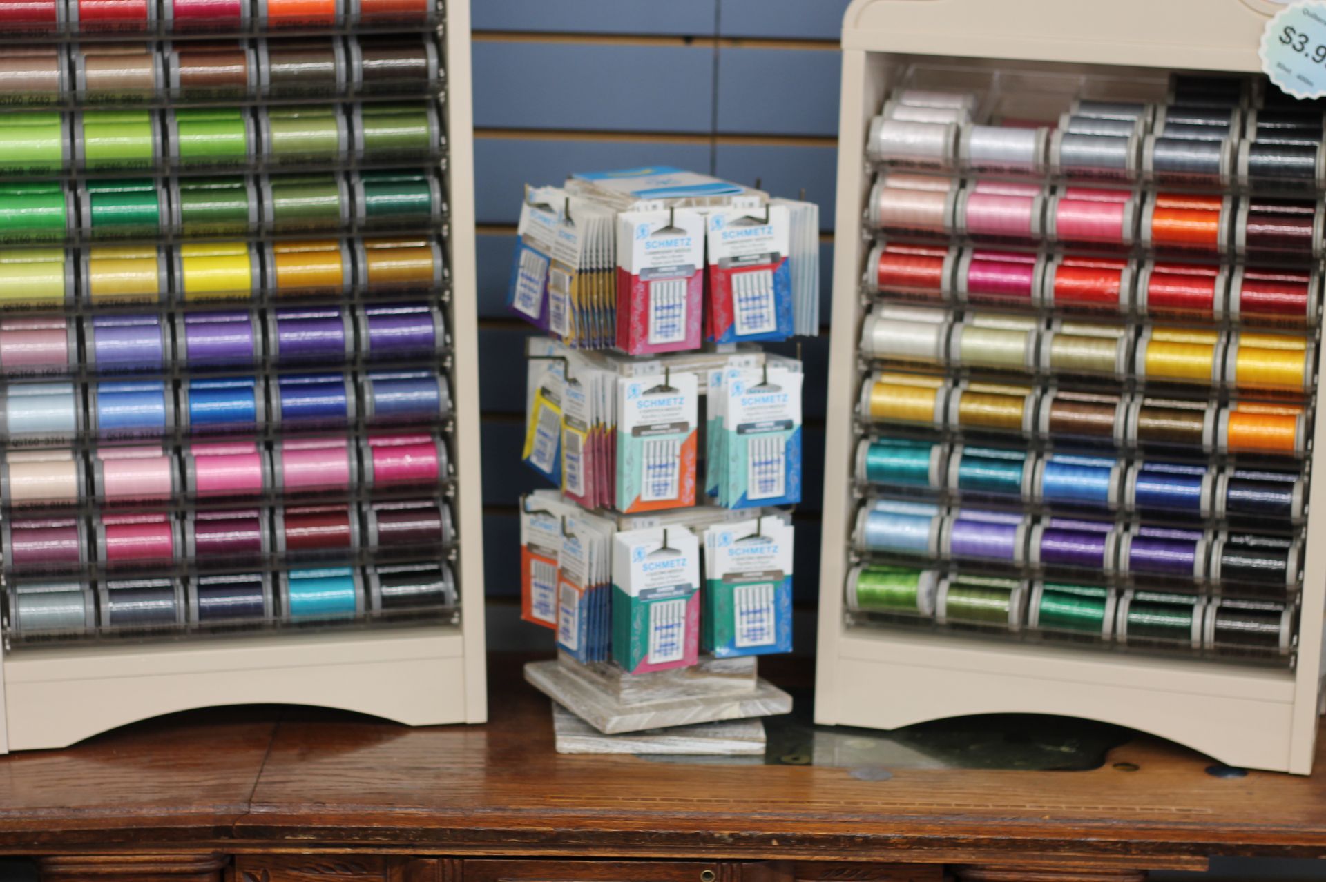 Shelves of colorful spools of thread and rotating display in a craft store.