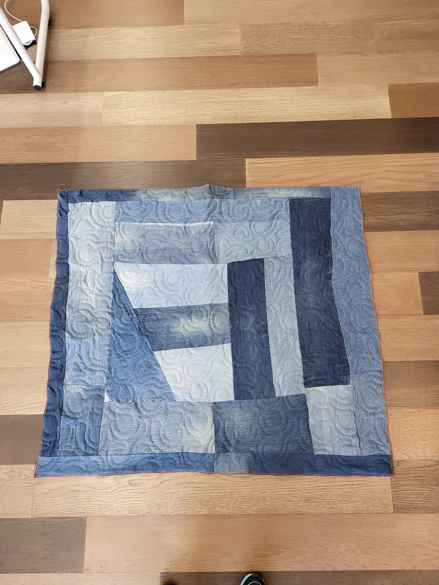 Blue denim patchwork rug on a wood floor.