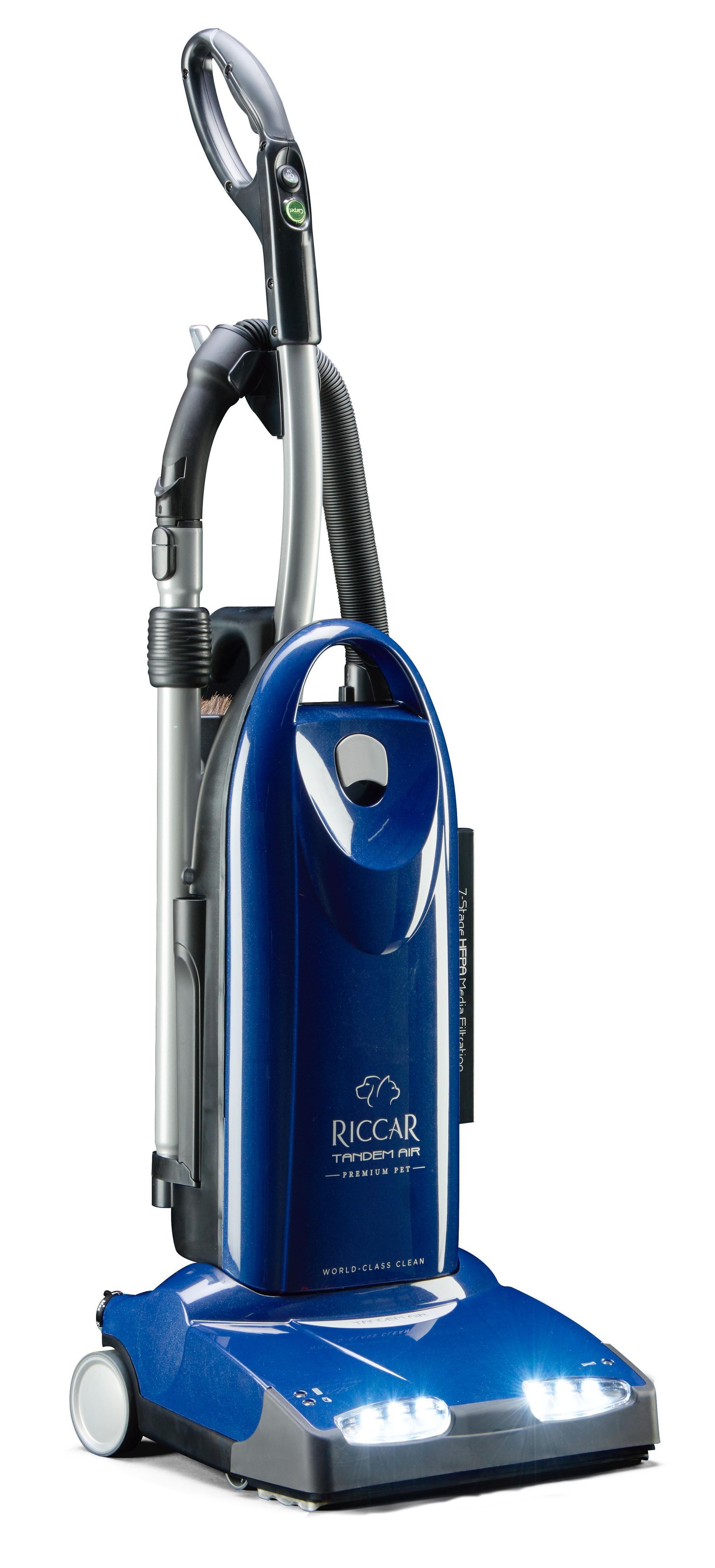 A navy blue upright vacuum cleaner standing vertically on a white background with a light at the base.