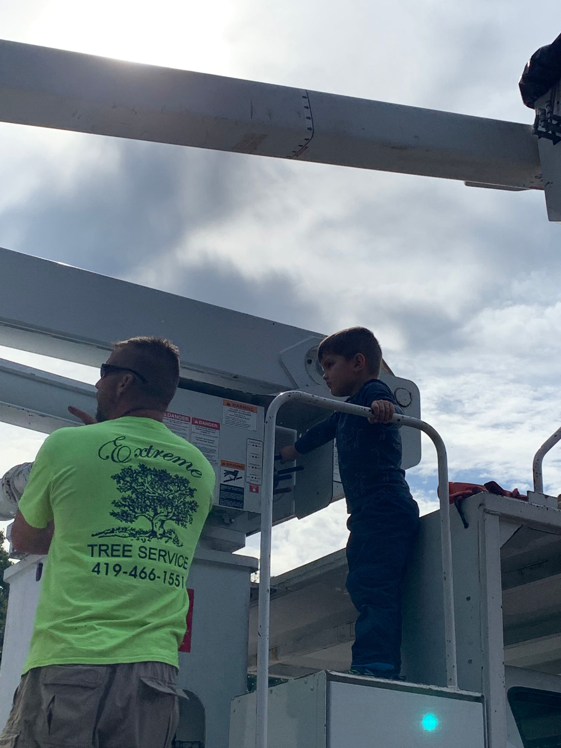Two workers in neon shirts on a raised platform assembling a large metal structure outdoors