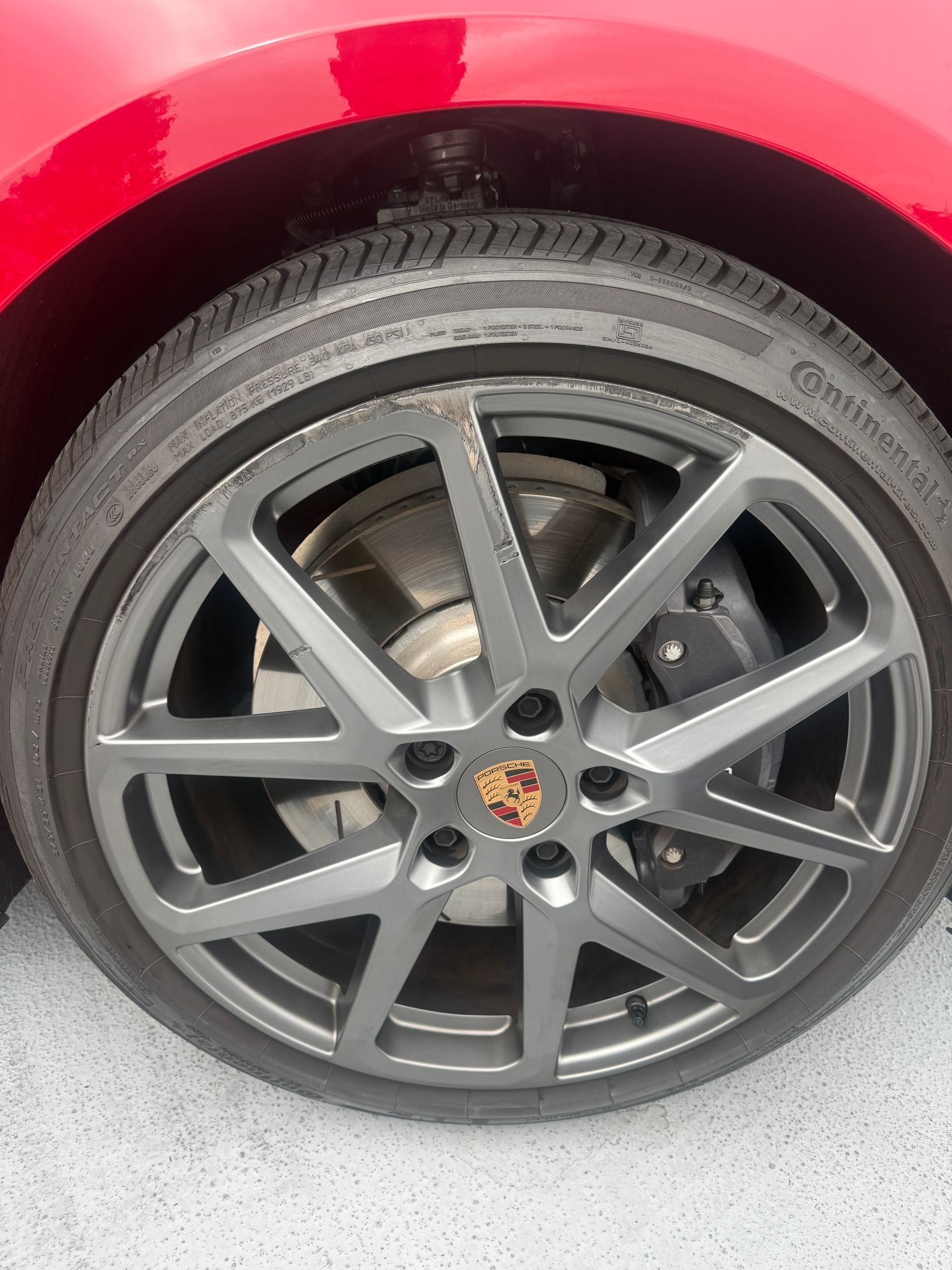 Close-up of a black Bentley wheel with red brake caliper and tire tread visible.