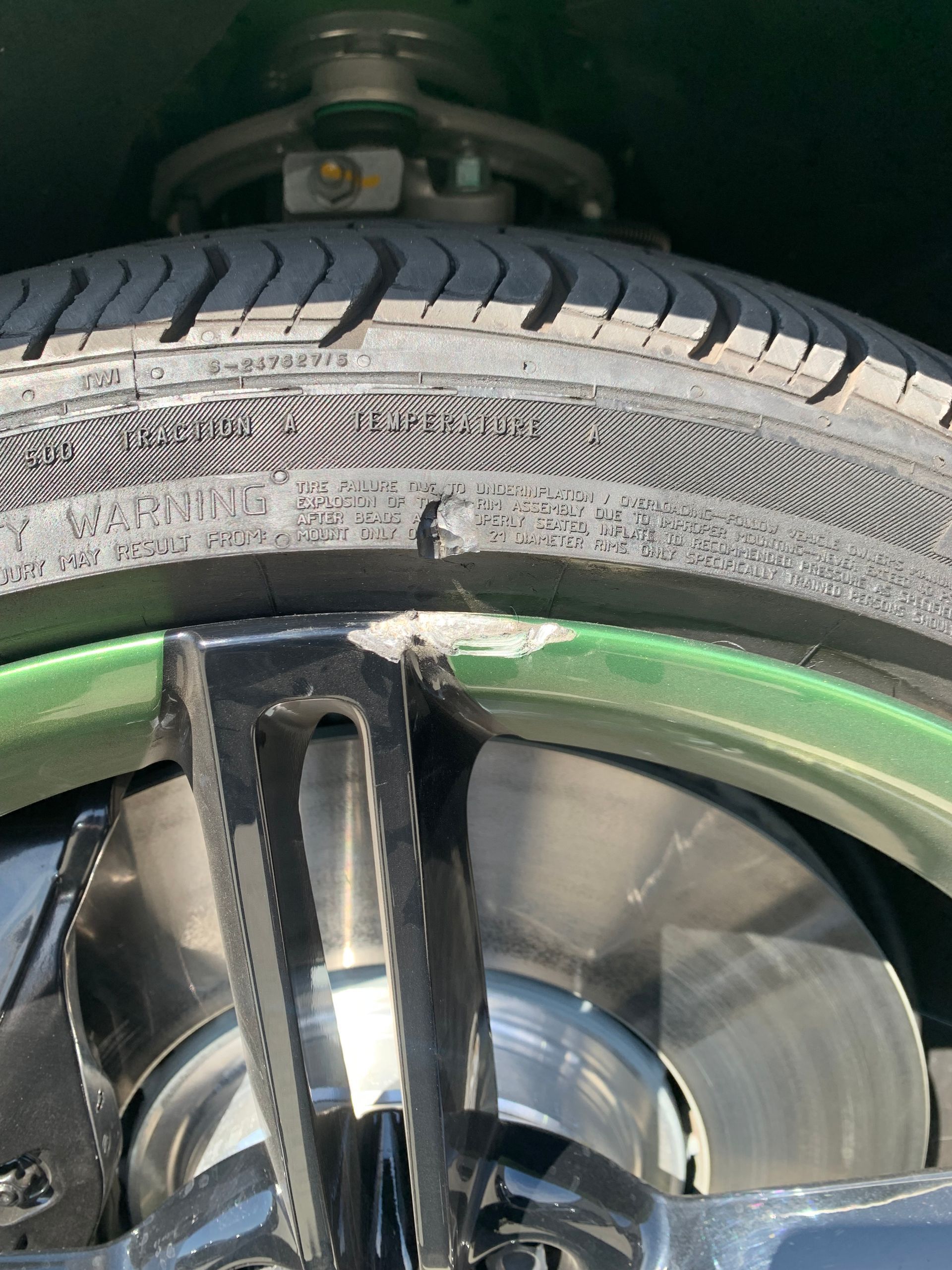 Close-up of a car wheel and tire with a damaged rim and exposed metal spokes.