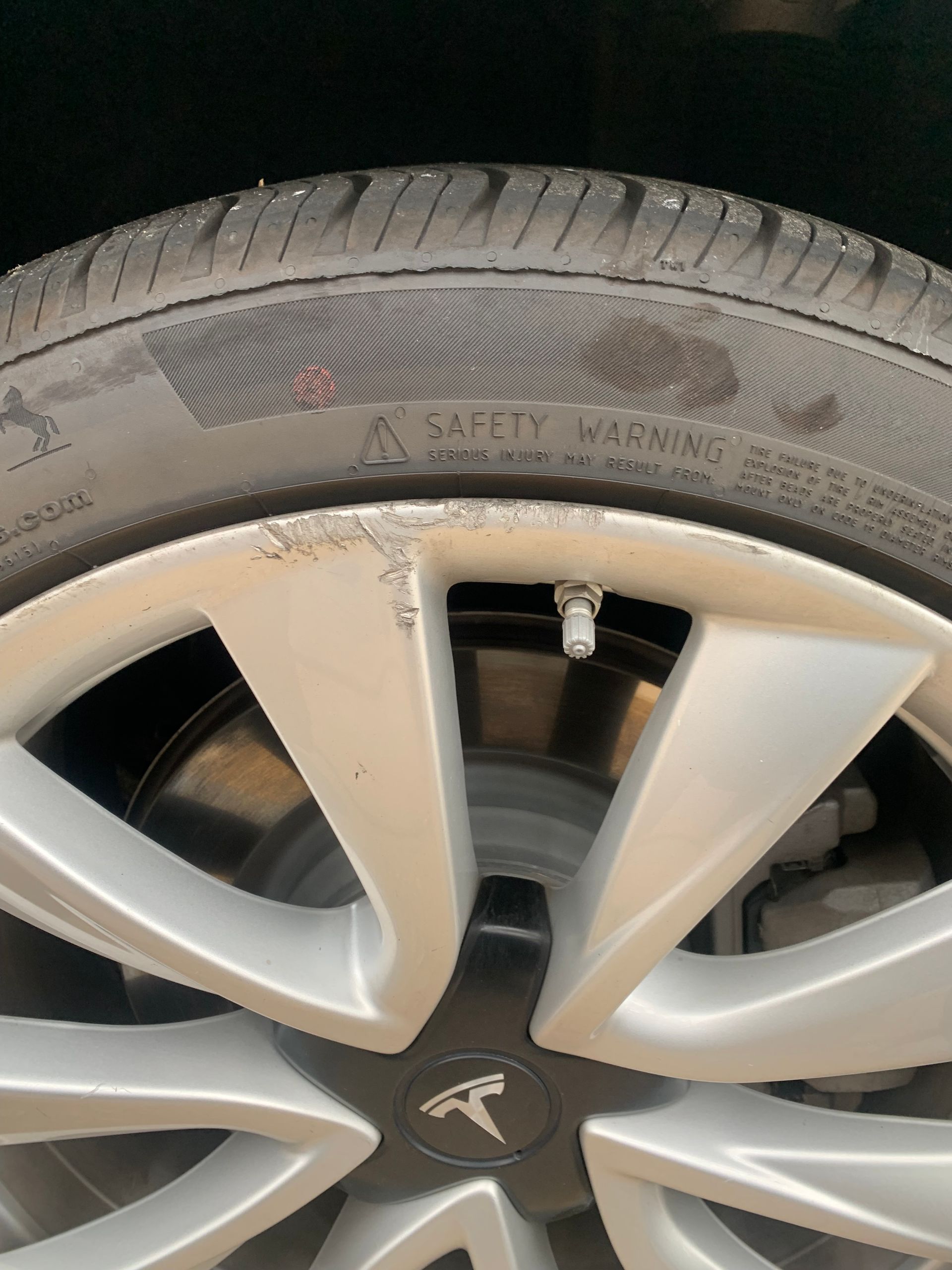 Close-up of a dusty Tesla wheel and tire with visible rim and valve stem.