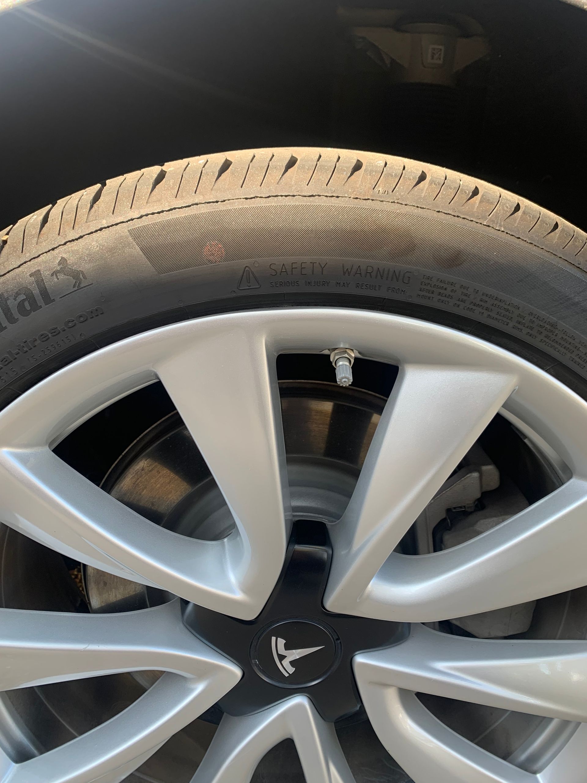 Close-up of a silver car wheel with a black tire and visible brake caliper.