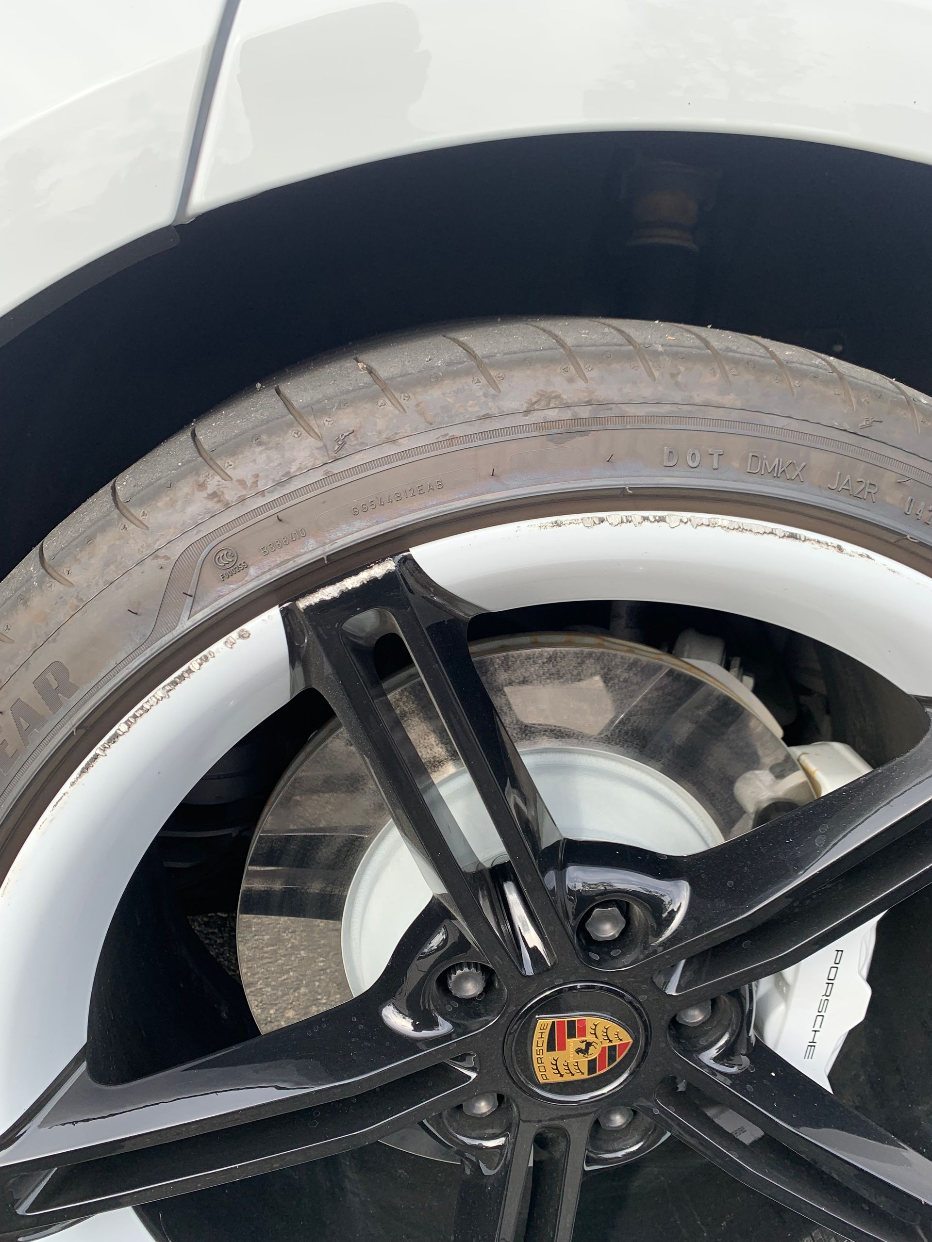 Close-up of a car wheel with a black alloy rim and white tire sidewall text.