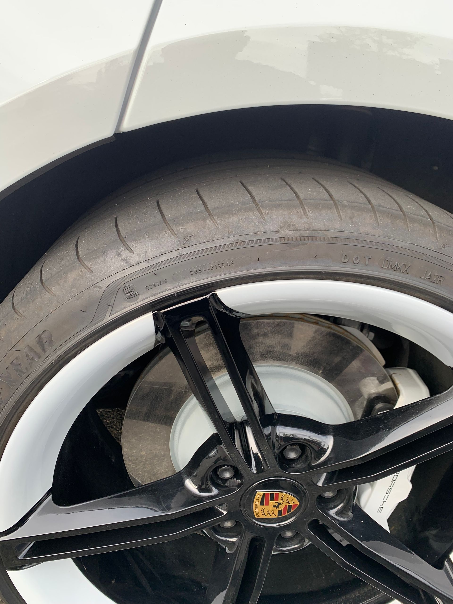 Close-up of a white car wheel with black alloy rim and tire under the fender.