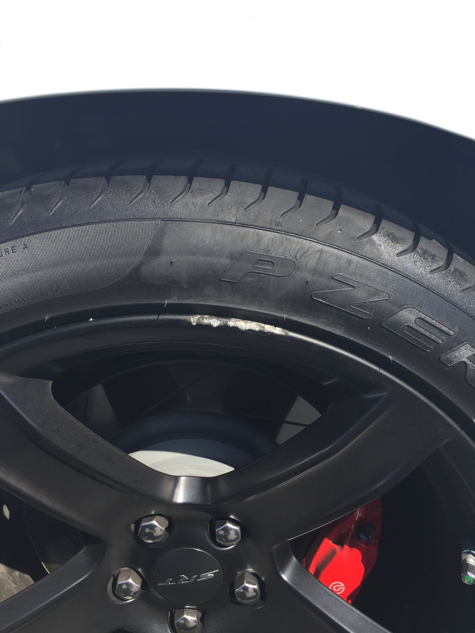 Close-up of a car wheel and tire with a red brake caliper visible behind the rim.