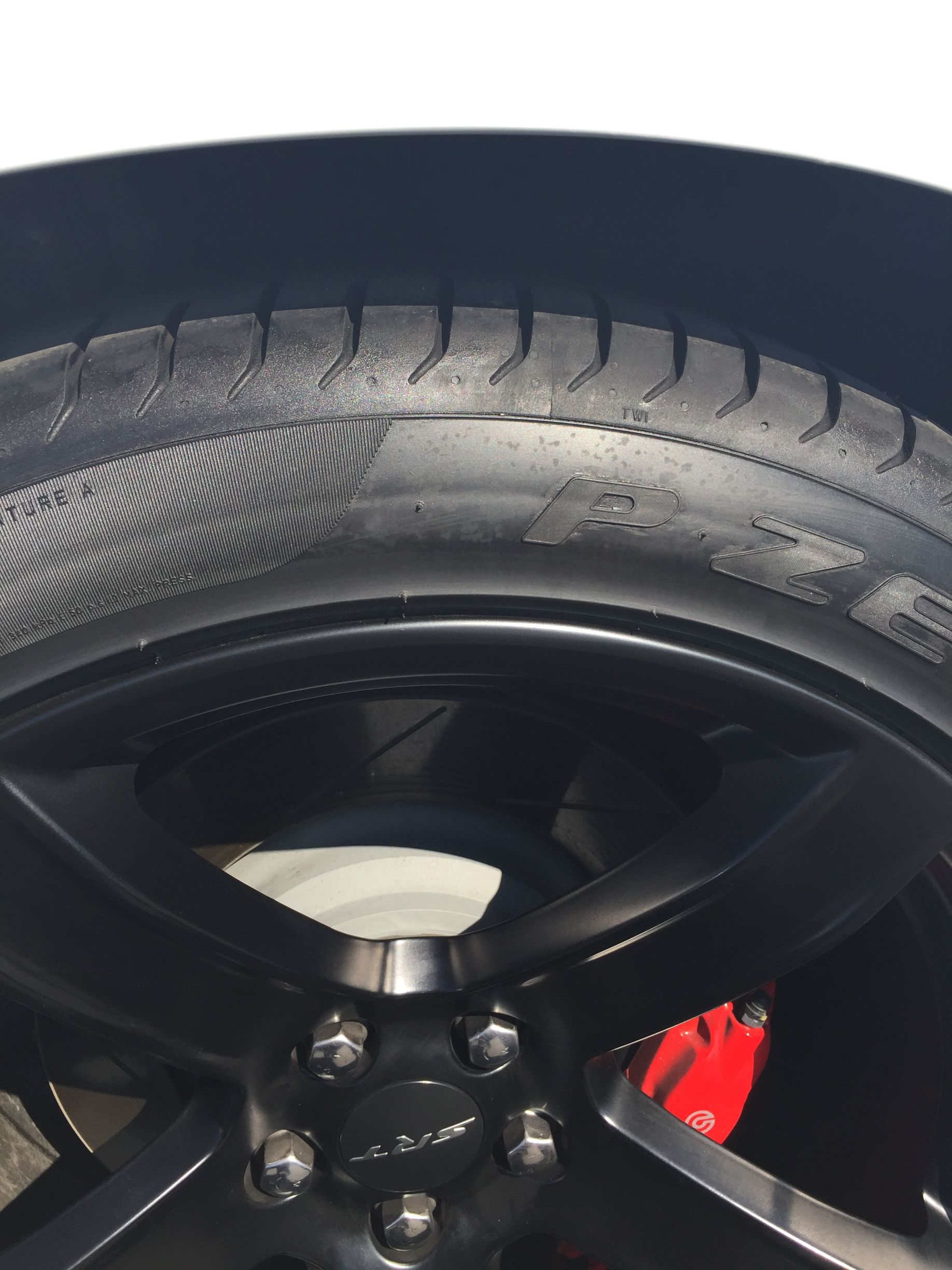 Close-up of a car wheel and tire with a black rim and red brake caliper.