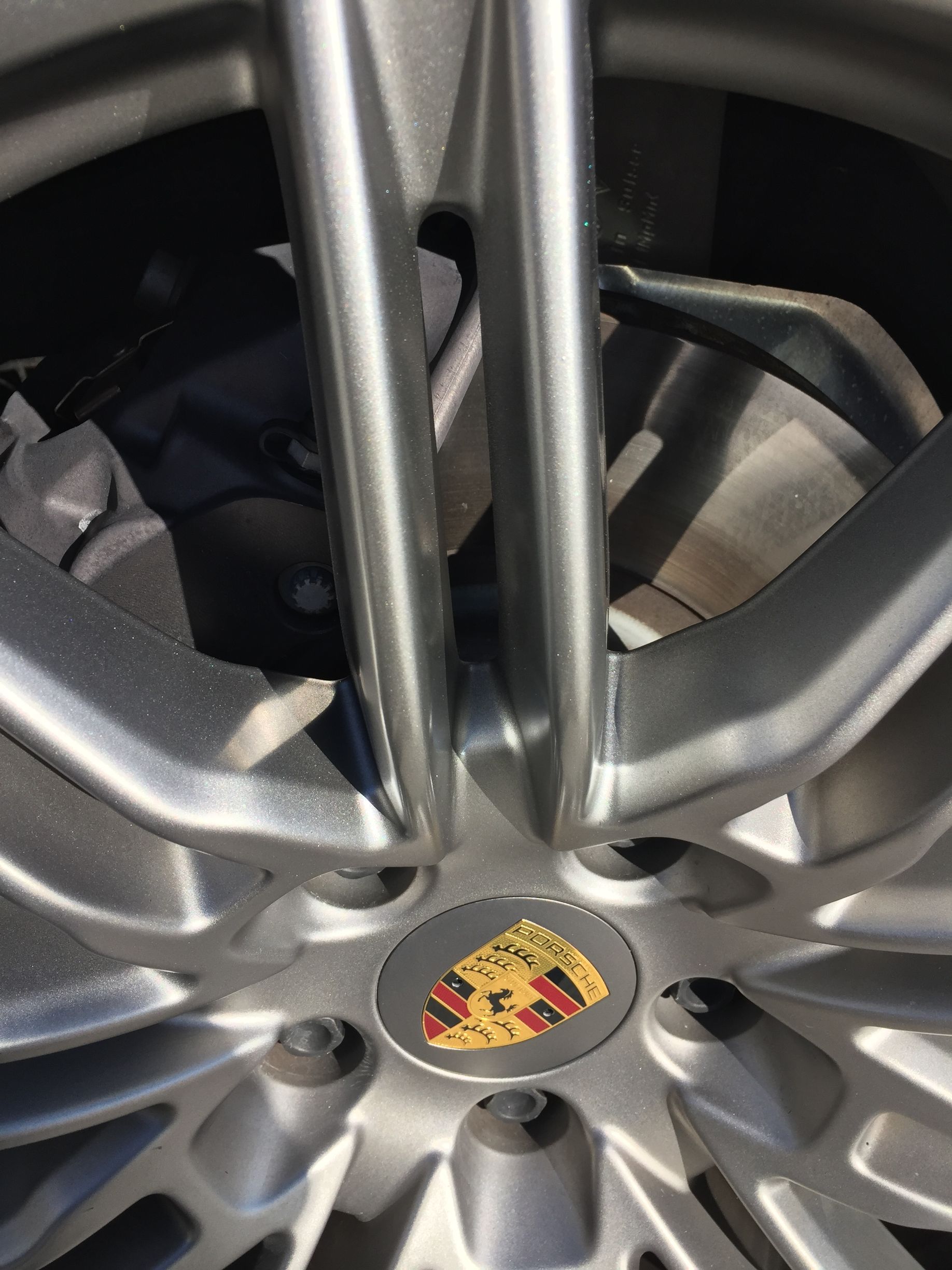 Close-up of a silver Porsche wheel rim with the crest center cap.