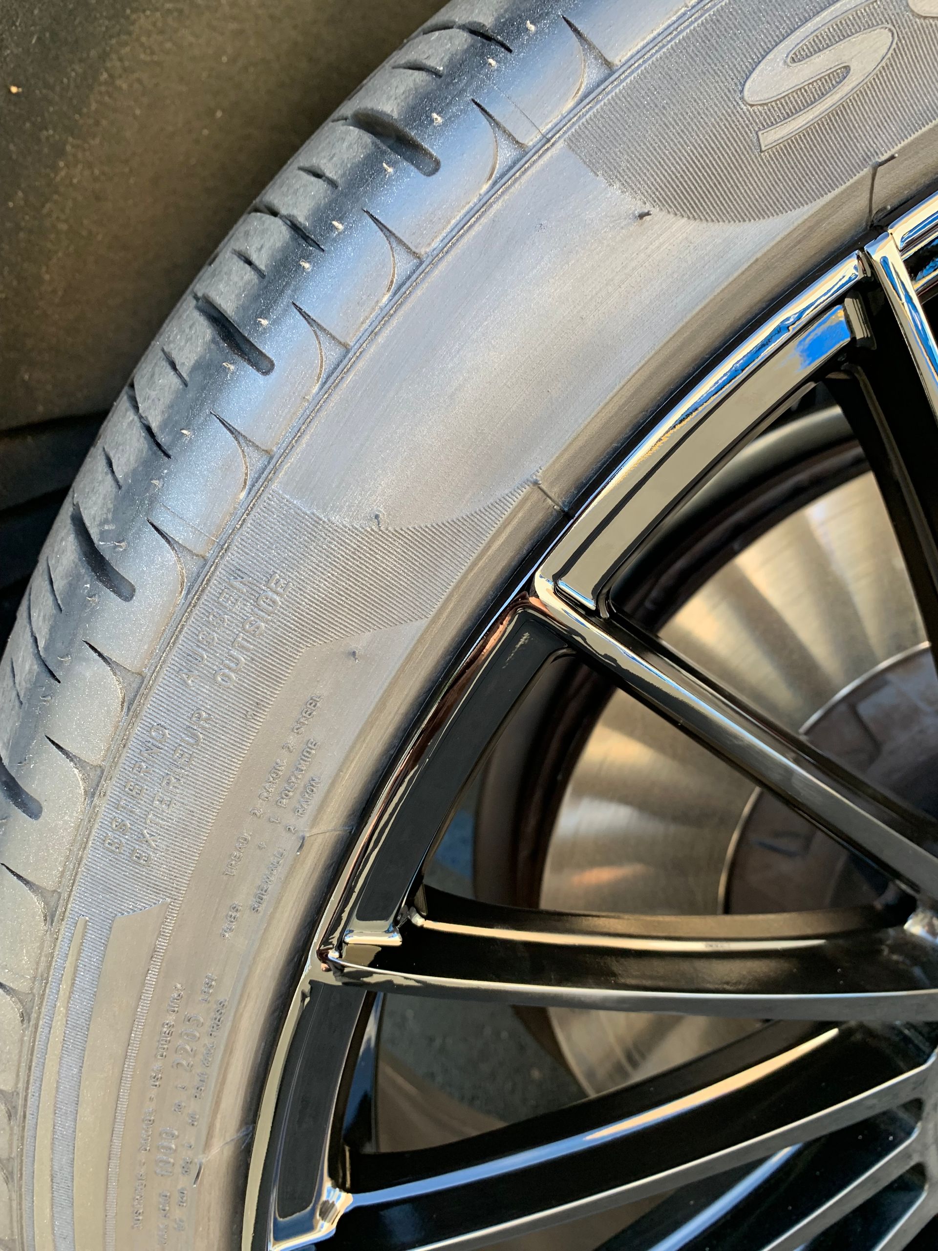 Close-up of a car tire with visible tread and a black alloy wheel.