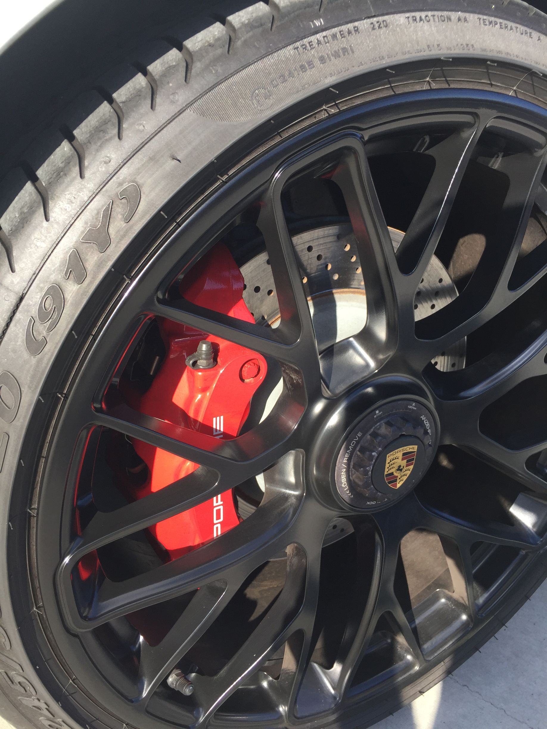 Black Porsche wheel with red brake caliper close-up.