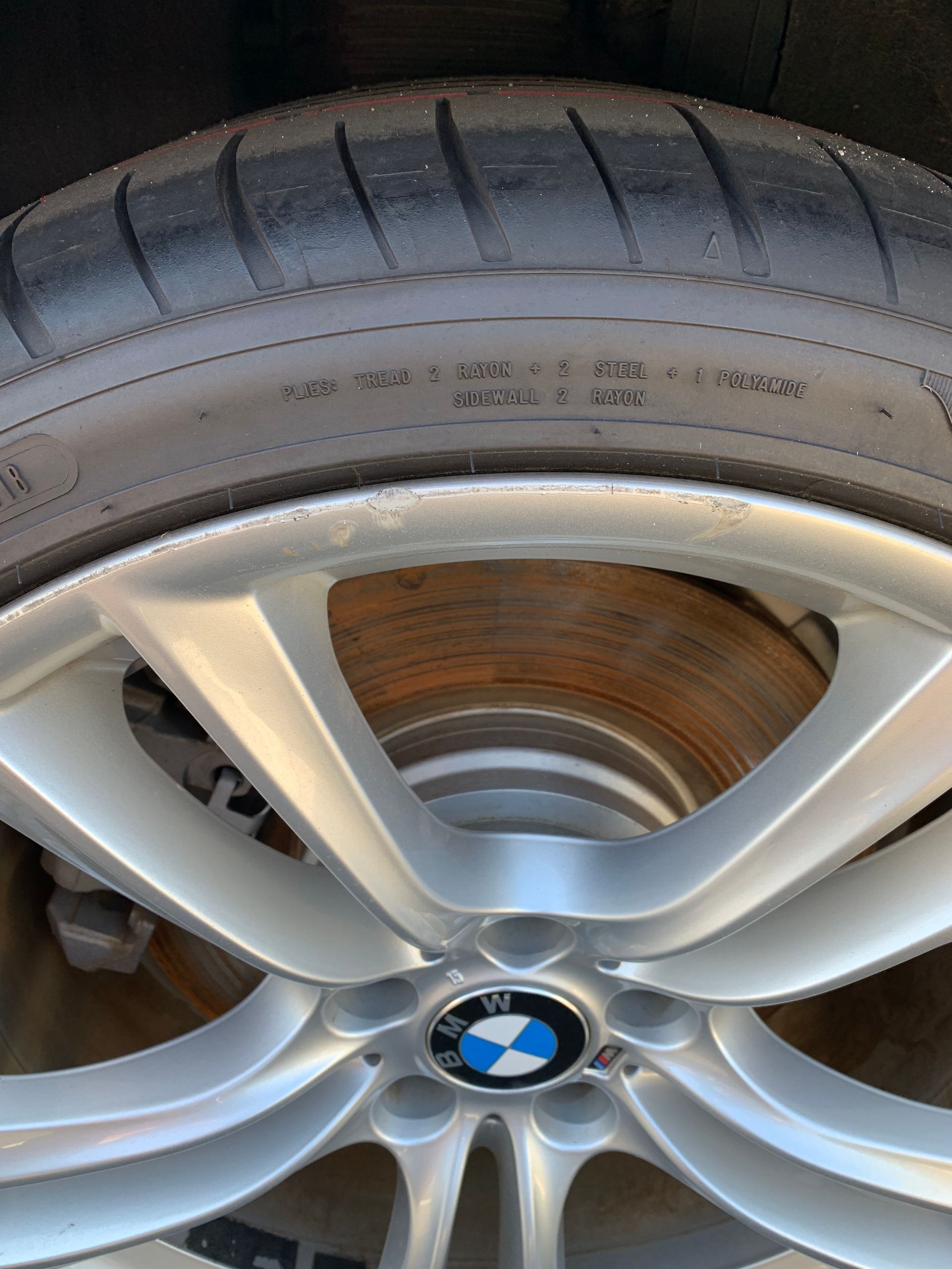 BMW alloy wheel with low-profile tire, showing brake disc behind the spokes.