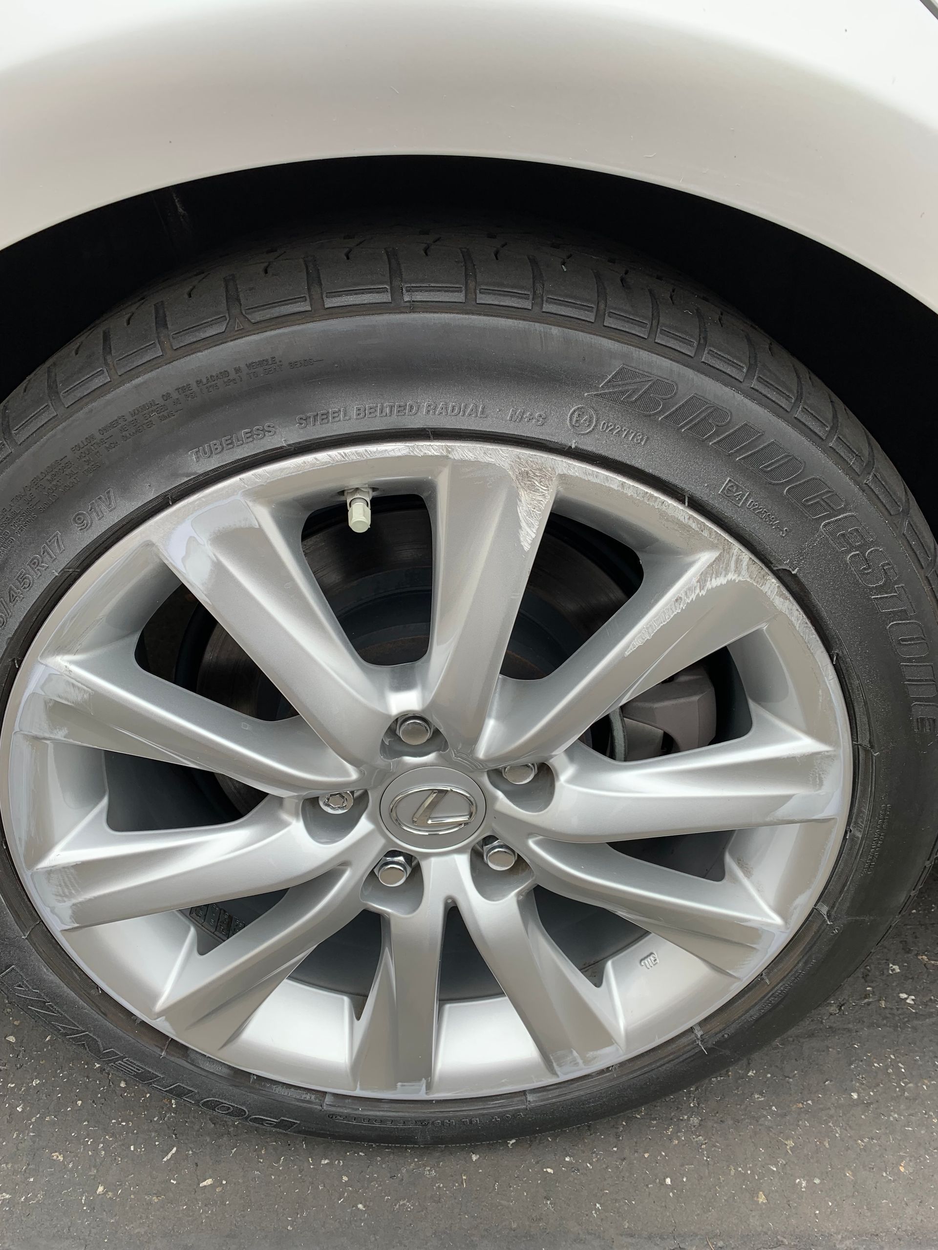 Close-up of a silver car wheel with tire and alloy rim on a white vehicle body.