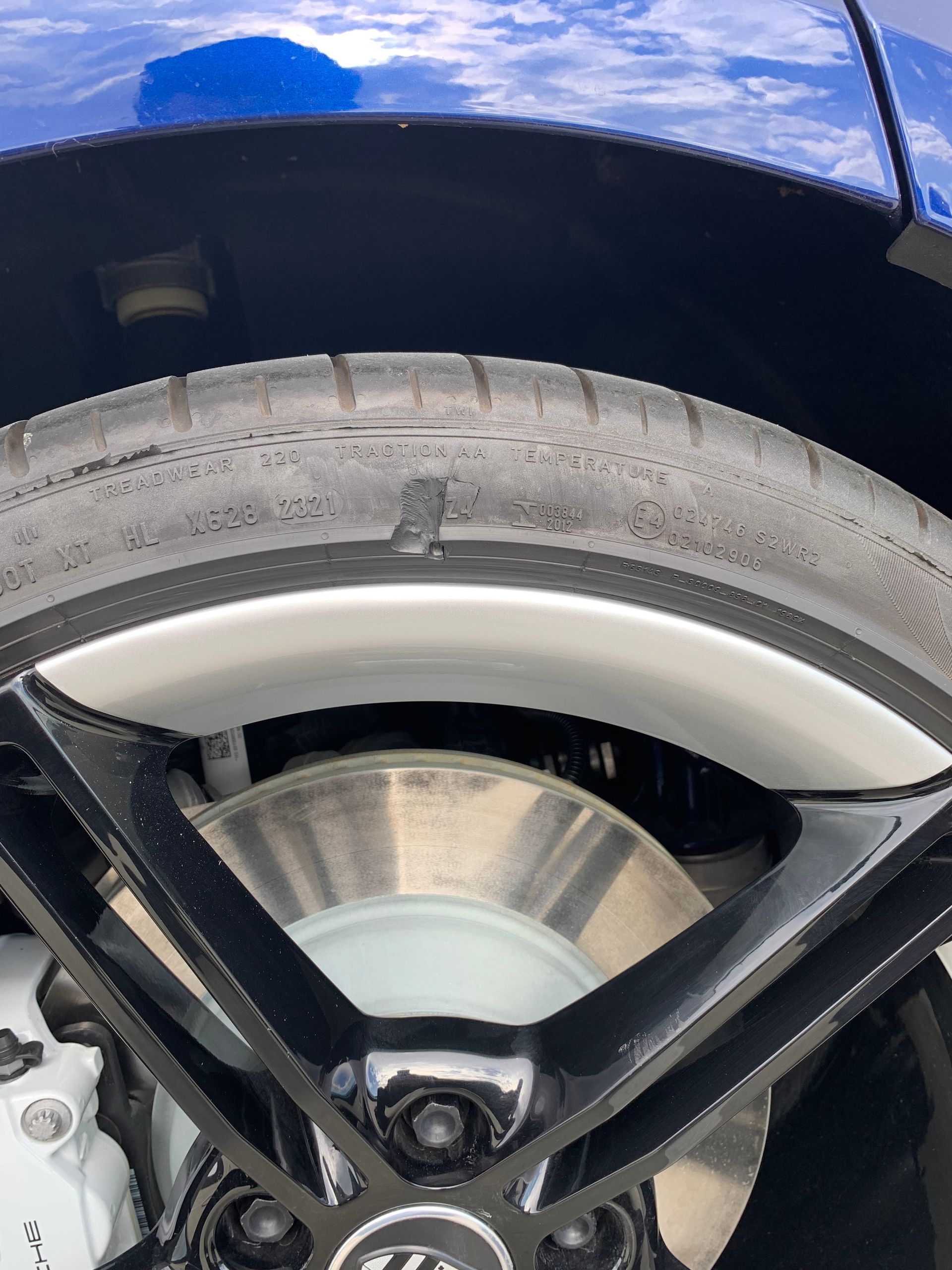 Close-up of a blue car wheel with black spokes and a visible tire under the fender.