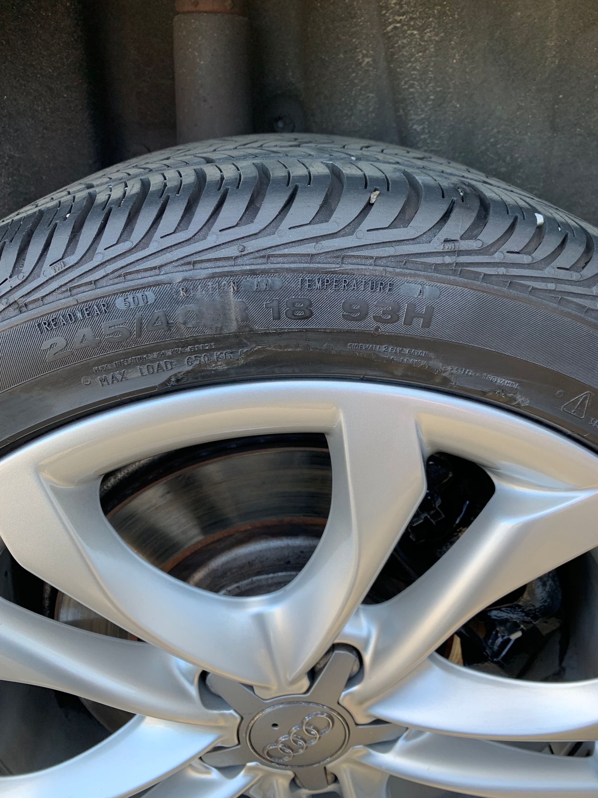 Close-up of a car wheel with a silver alloy rim and worn black tire tread.