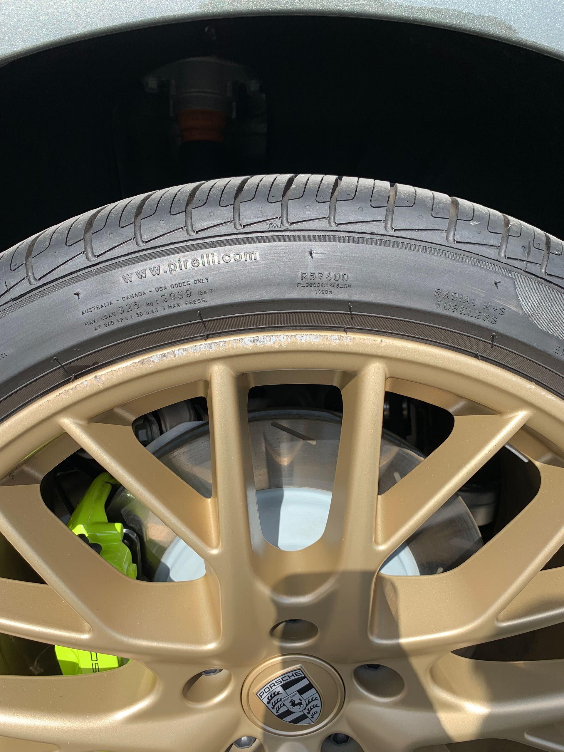 Close-up of a gold car wheel and tire with a neon green brake caliper behind it.