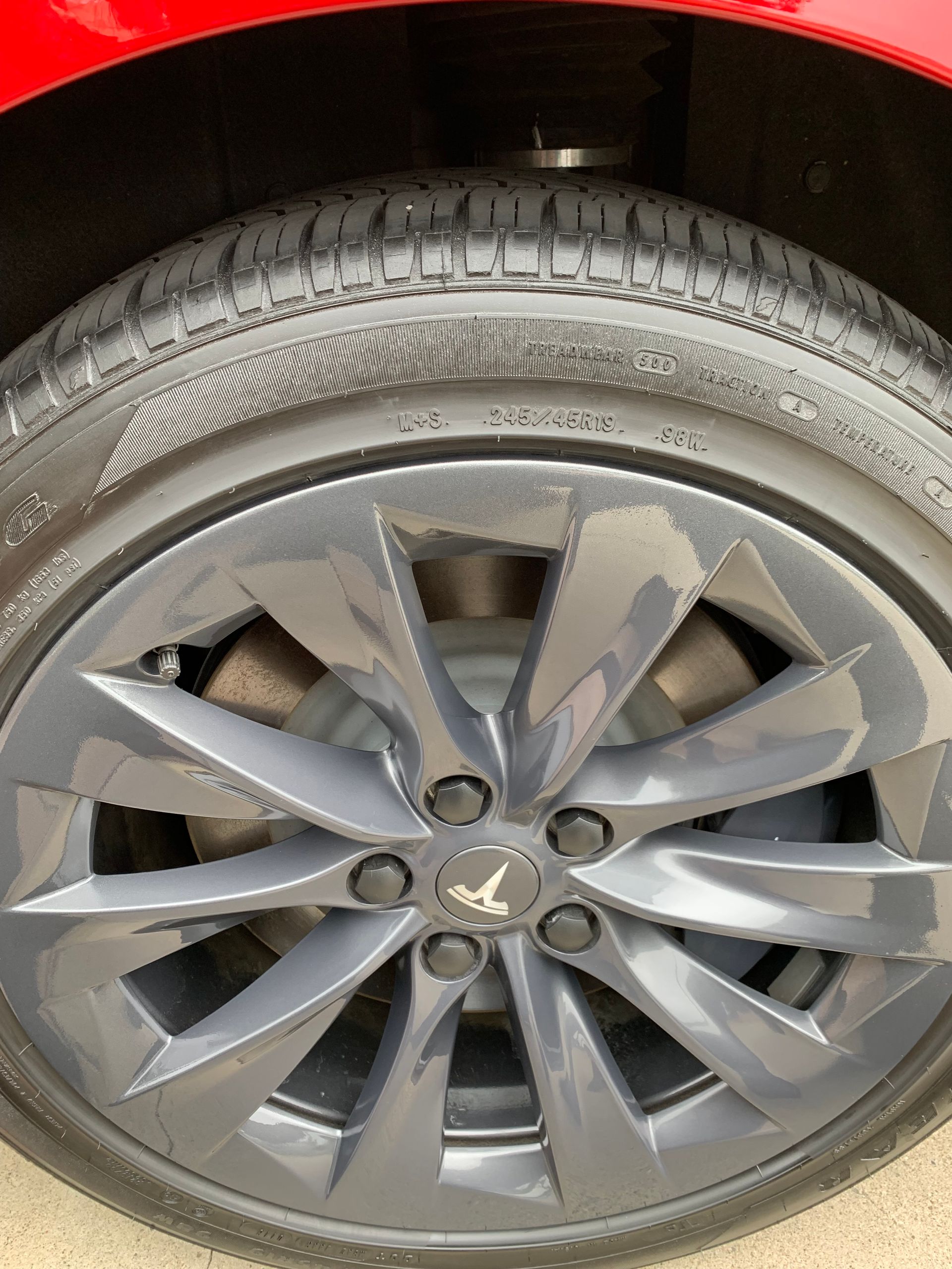 Close-up of a gray car wheel with a scratched alloy rim and visible tire tread.