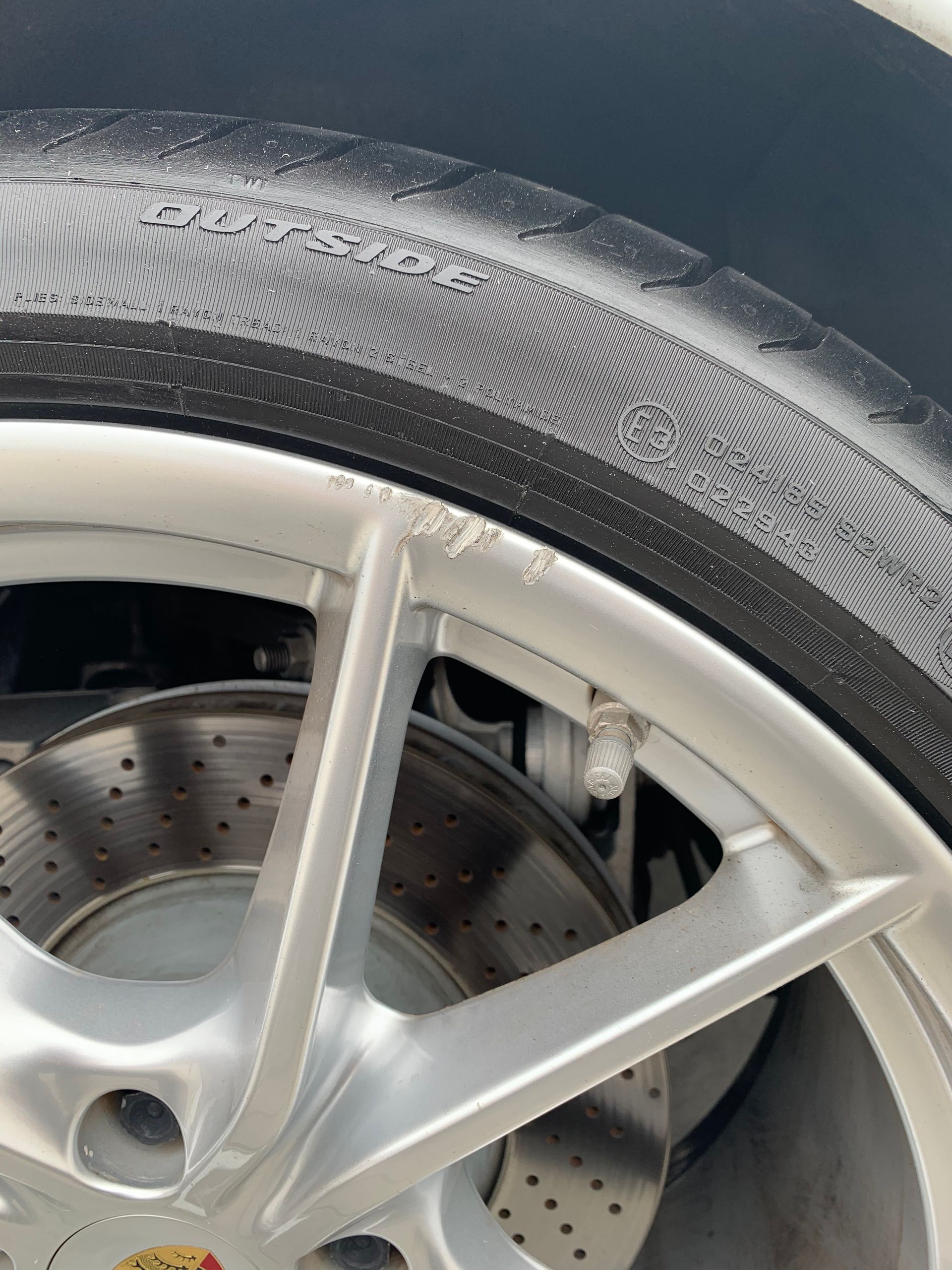 Close-up of a car wheel with silver rim, black tire, and visible brake disc.