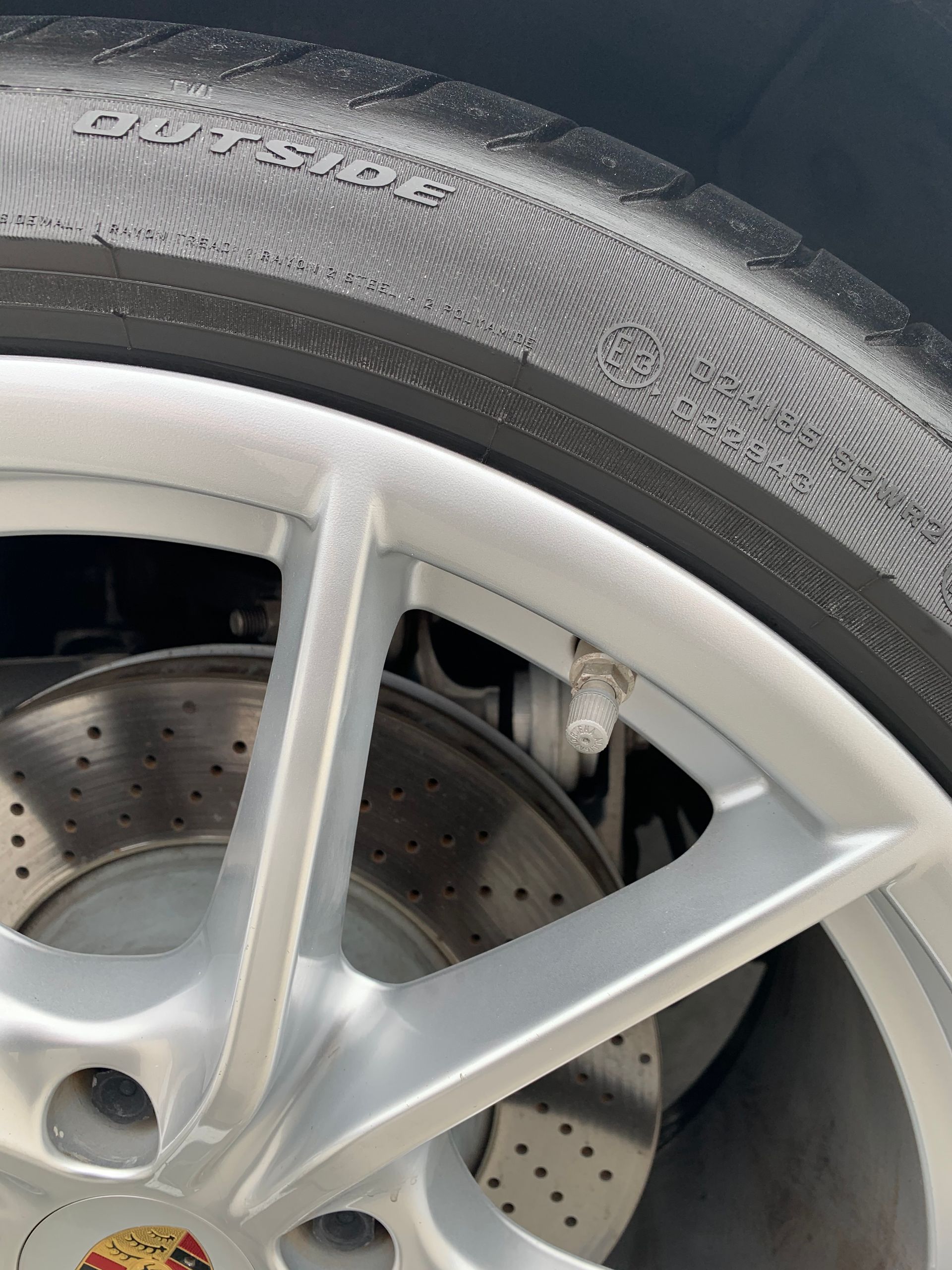 Close-up of a car wheel with a silver rim and visible brake disc behind it.