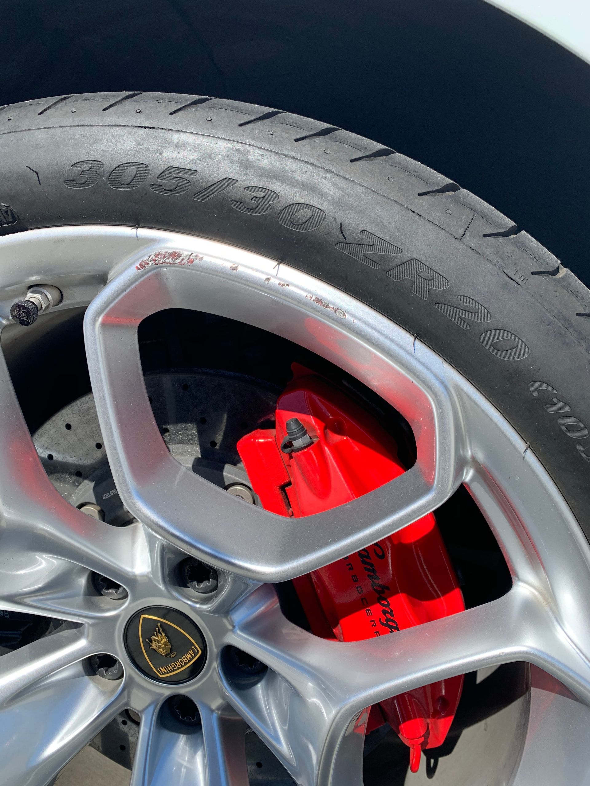 Close-up of a car wheel with silver alloy rim, black tire, and bright red brake caliper.