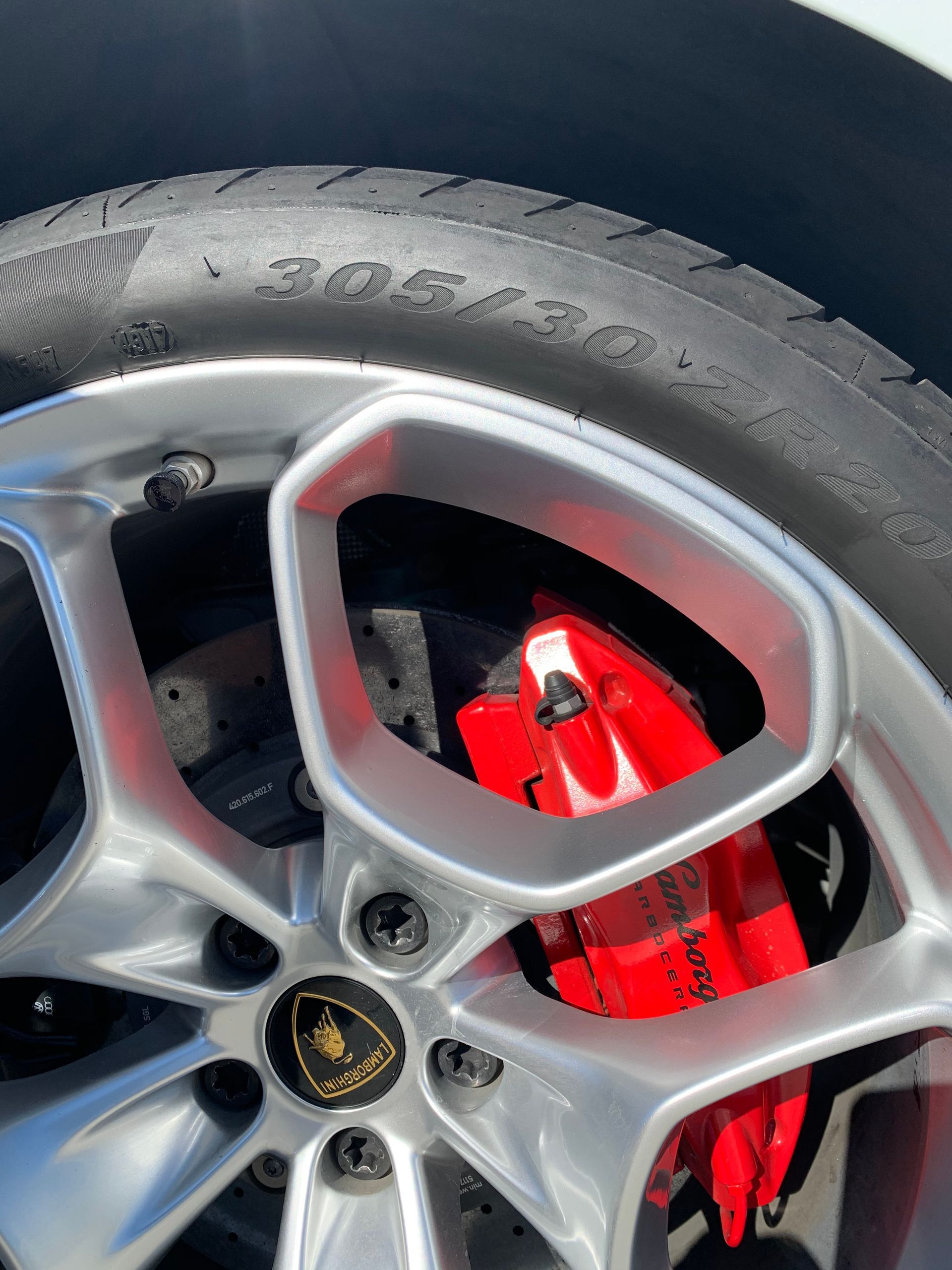Close-up of a silver car wheel with a bright red brake caliper and black tire.