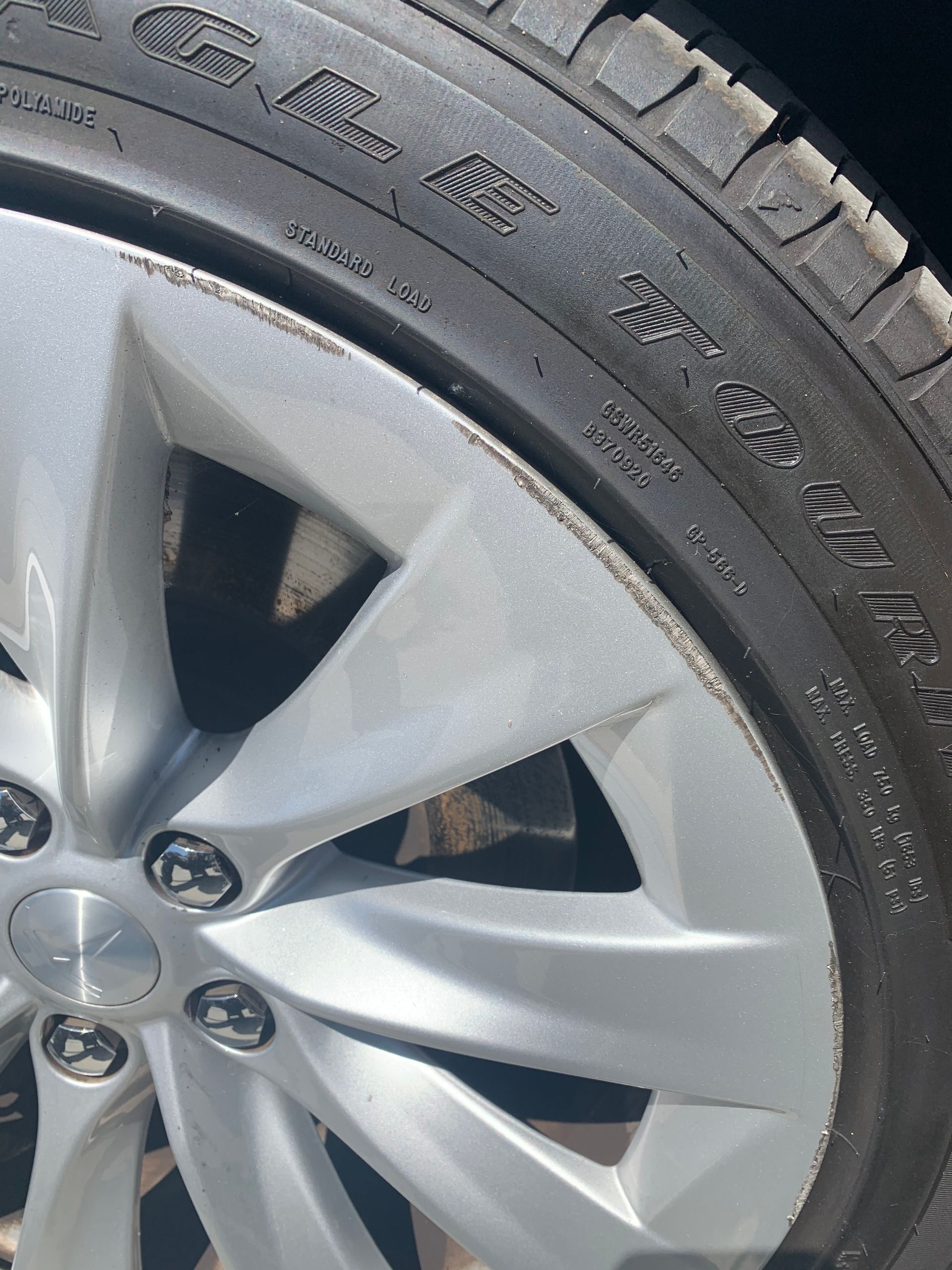 Close-up of a silver car wheel and tire with visible tread and sidewall text.