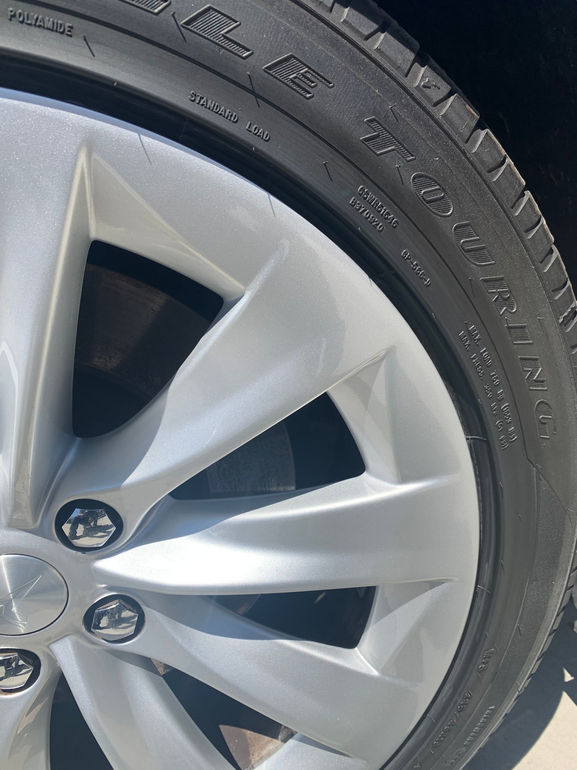 Close-up of a silver car wheel with hubcap and black tire tread, showing minor scuffs.