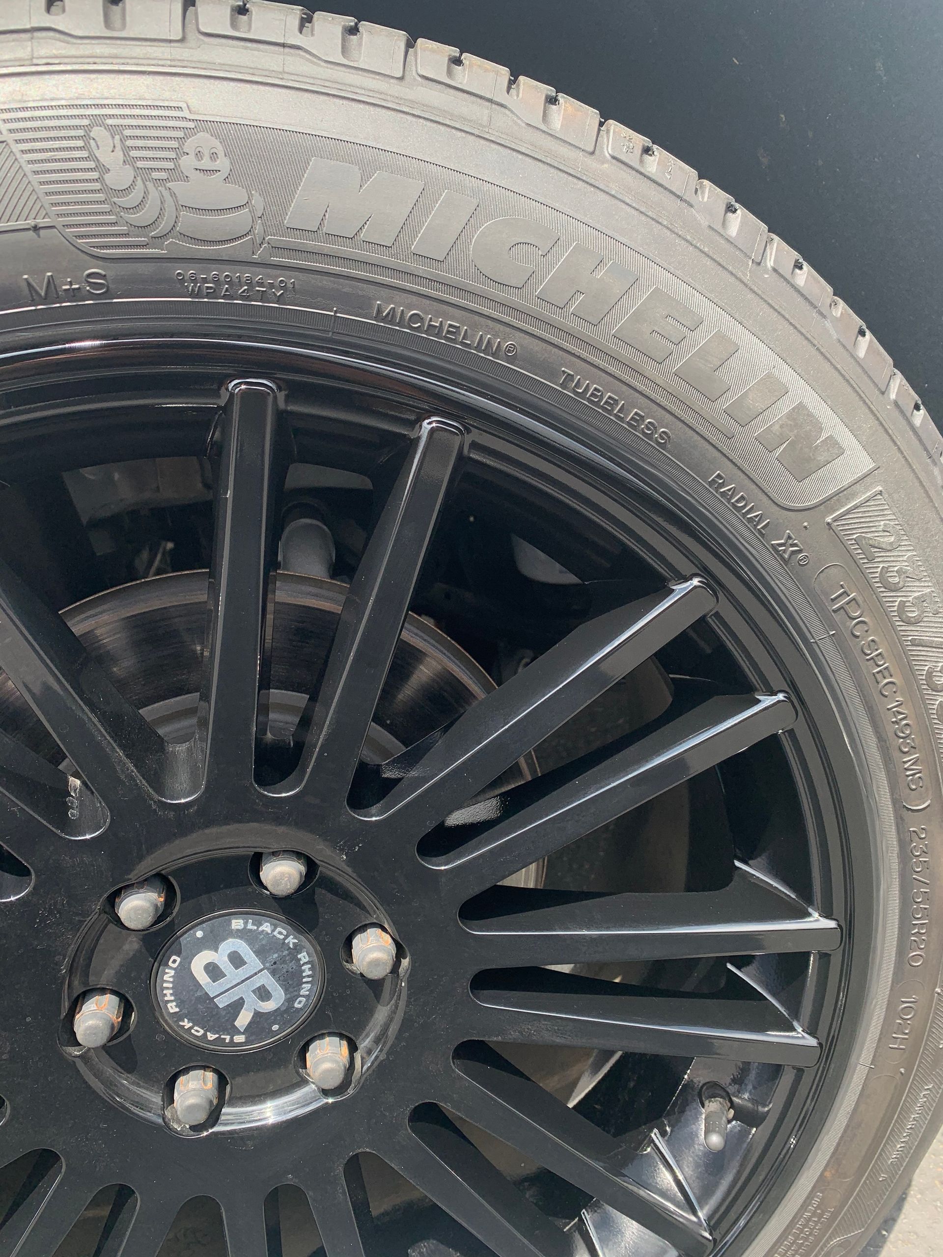 Close-up of a black car wheel and tire with a multi-spoke rim and central logo.